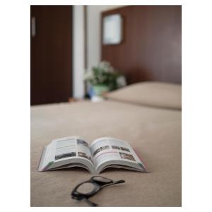 a book with a pair of glasses sitting on a bed at Hotel Margherita in Monterosso al Mare