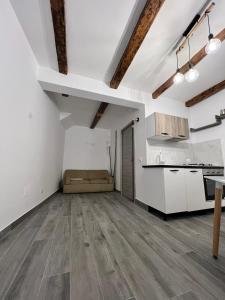 una cucina a pianta aperta e un soggiorno con pareti bianche e pavimenti in legno di B&b La casett a Crotone