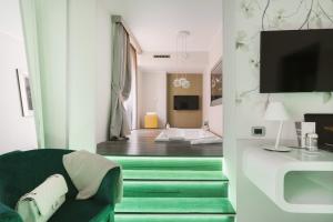 sala de estar con silla verde y TV en Montenapoleone Suites, en Milán