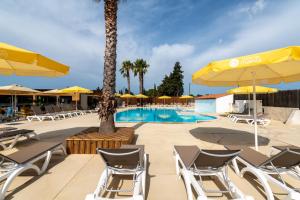 a resort with a pool and chairs and a palm tree at Camping maeva Escapades Les Cottages de Perpignan in Perpignan