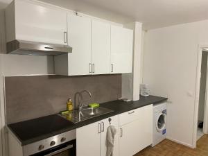 una cocina con armarios blancos y fregadero en Bel appartement spacieux, lumineux avec parking en Ris-Orangis