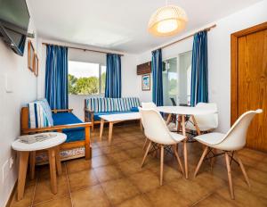 - un salon avec une table, des chaises et un canapé dans l'établissement Globales Apartamentos Cala Viñas ONLY ADULTS 16, à Cala Vinyes