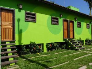 a green house with wooden doors and a yard at Sun Suítes in Ubatuba