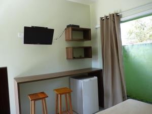 a room with a refrigerator and two stools and a tv at Sun Suítes in Ubatuba +8 photos