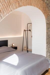 a bedroom with a white bed and a brick wall at DOM1872 apartments in Trieste