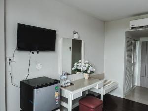 a living room with a table and a tv on the wall at River Grand Hotel in Hat Yai