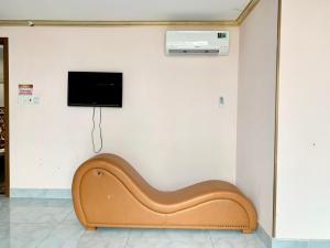 OYO 1170 Nhan Duc Hotel في مدينة هوشي منه: مقعد خشبي في غرفة مع تلفزيون على جدار