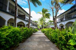 a path between two buildings with palm trees at Maison Du Nord in Pointe aux Cannoniers