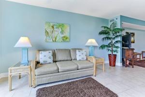een woonkamer met een bank en een palmboom bij 203 Terraces at Beachside in Fernandina Beach