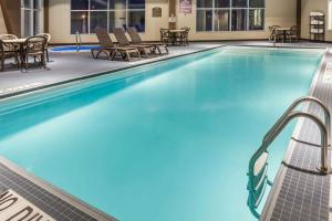 a swimming pool with chairs and a table at Microtel Inn & Suites by Wyndham - Timmins in Timmins