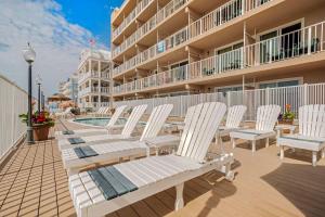 a row of white chairs sitting on a deck next to a building at Comfort Inn Ocean City Boardwalk in Ocean City