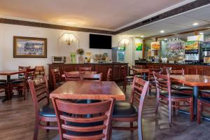 a restaurant with wooden tables and chairs and a bar at Quality Inn Montgomeryville-Philadelphia in Montgomeryville