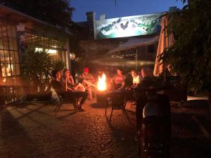 a group of people sitting around a fire at night at Sandino Hostel - Solo Traveler Sanctuary in Berlin