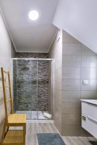 a bathroom with a shower and a wooden chair at Costa Mar III in Peniche