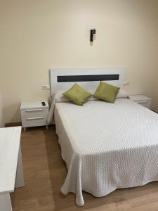 - une chambre avec un grand lit blanc et des oreillers verts dans l'établissement Casa Gala, à Santa María del Páramo