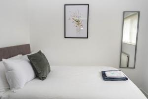 een slaapkamer met een wit bed met een foto aan de muur bij Comfortable 3 Bed House with Parking, WiFi & Patio by Ark SA in Handsworth