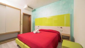 a bedroom with a red bed with a stuffed animal on it at Hotel Venezia in Caorle