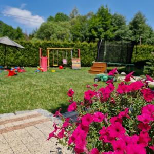 un jardín con flores rosas y un parque infantil en Willa jak u Babci, en Wisła