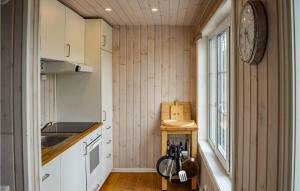 Cozy Home In Brttum With Kitchen في Skrukkerud: مطبخ بجدران خشبية وساعة على الحائط