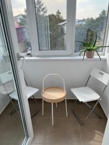 una silla y dos sillas sentadas en una ventana en Alma apartments en Suceava