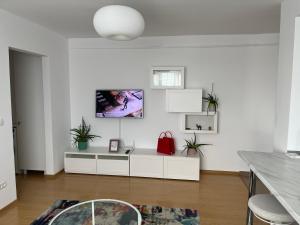una sala de estar con muebles blancos y un bolso rojo en Alma apartments en Suceava