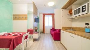 a kitchen and living room with a table and a red couch at Hotel Venezia in Caorle