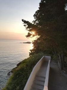 a staircase leading down to the ocean with the sun setting at Amy Villa in Agnone