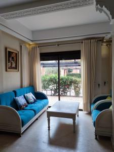 een woonkamer met een blauwe bank en een tafel bij Bel Appartement dans une résidence Fermée avec piscine in Marrakesh