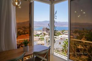 een eetkamer met een tafel en een groot raam bij YalaRent Orchid Boutique Apartments in Eilat