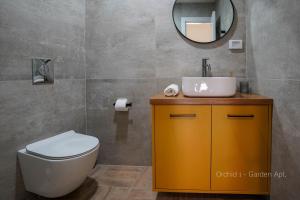ein Badezimmer mit einem WC, einem Waschbecken und einem Spiegel in der Unterkunft YalaRent Orchid Boutique Apartments in Eilat