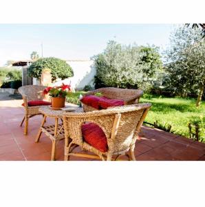 奧古斯塔的住宿－Villa Angela，庭院设有藤椅和带红色枕头的桌子。