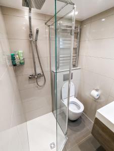 W łazience znajduje się toaleta i przeszklona kabina prysznicowa. w obiekcie Modern 3 Bedroom Apartment in Kensington w Londynie