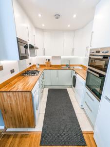 een keuken met witte kasten en houten aanrechtbladen bij Modern 3 Bedroom Apartment in Kensington in Londen
