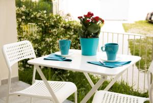 een witte tafel en stoelen op een balkon met bloemen bij InnPisaRentals - Loft in Pisa Historical Center in Pisa