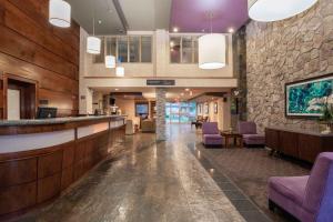 a hotel lobby with a bar and purple chairs at Sandman Hotel & Suites Regina in Regina