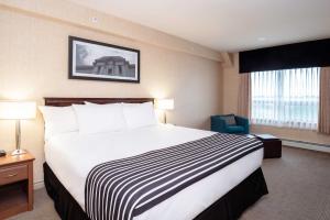 Pokój hotelowy z dużym łóżkiem i krzesłem w obiekcie Sandman Hotel & Suites Regina w mieście Regina
