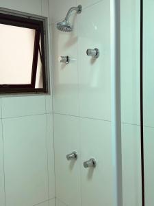 a shower with a glass door and a window at NOVO pitangueiras service 2, dois dormitórios, 100 m da praia, duas vagas de garagem, completo in Guarujá