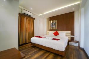 a bedroom with a large bed with white sheets and red pillows at Emarald Hotel Calicut in Kozhikode