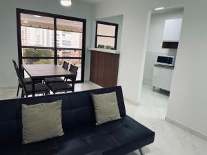 a living room with a black couch and a table at NOVO pitangueiras service 2, dois dormitórios, 100 m da praia, duas vagas de garagem, completo in Guarujá