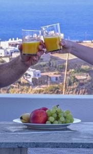 two people holding glasses of orange juice next to a plate of fruit at Syros Luxury Living in Rózia