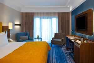 a hotel room with a bed and chairs and a television at Mövenpick Hotel Istanbul Asia Airport in Istanbul