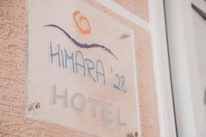 a sign on a wall with a sign for ahmahma at Himara 28 Hotel in Himare
