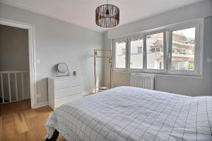 ein weißes Schlafzimmer mit einem Bett und einem Fenster in der Unterkunft Maison face à Nausicaa in Boulogne-sur-Mer