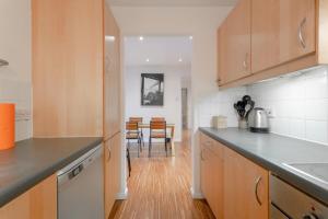 a kitchen with wooden cabinets and a dining room at A Spacious 2 Bedroom Apartment In Aldgate East in London