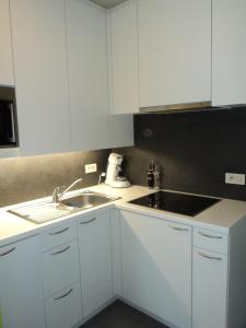 eine Küche mit weißen Schränken und einem Waschbecken in der Unterkunft For Ever in Nieuwpoort