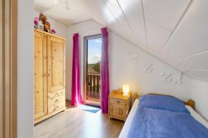 a bedroom with a bed and a window with purple curtains at Ferienhaus Viola in Kirchheim