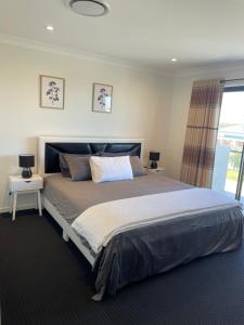 um quarto com uma cama grande e duas mesas em Waterside Holiday Home em Redcliffe
