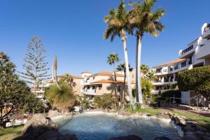 una piscina frente a un edificio con palmeras en Precioso apartamento en el Sur de Tenerife, en San Miguel de Abona