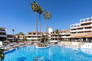 una gran piscina con sillas y palmeras en un complejo en Precioso apartamento en el Sur de Tenerife, en San Miguel de Abona