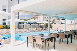 a poolside patio with tables and chairs and a swimming pool at Cool Šilo Appartement Resort in Šilo
